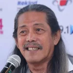 Acil Bimbo, musisi legendaris dari grup Bimbo, meninggal dunia pada usia 82 tahun. Foto ini menampilkan Acil Bimbo saat masih aktif di panggung, mencerminkan dedikasinya yang tak terbatas pada dunia musik dan hiburan